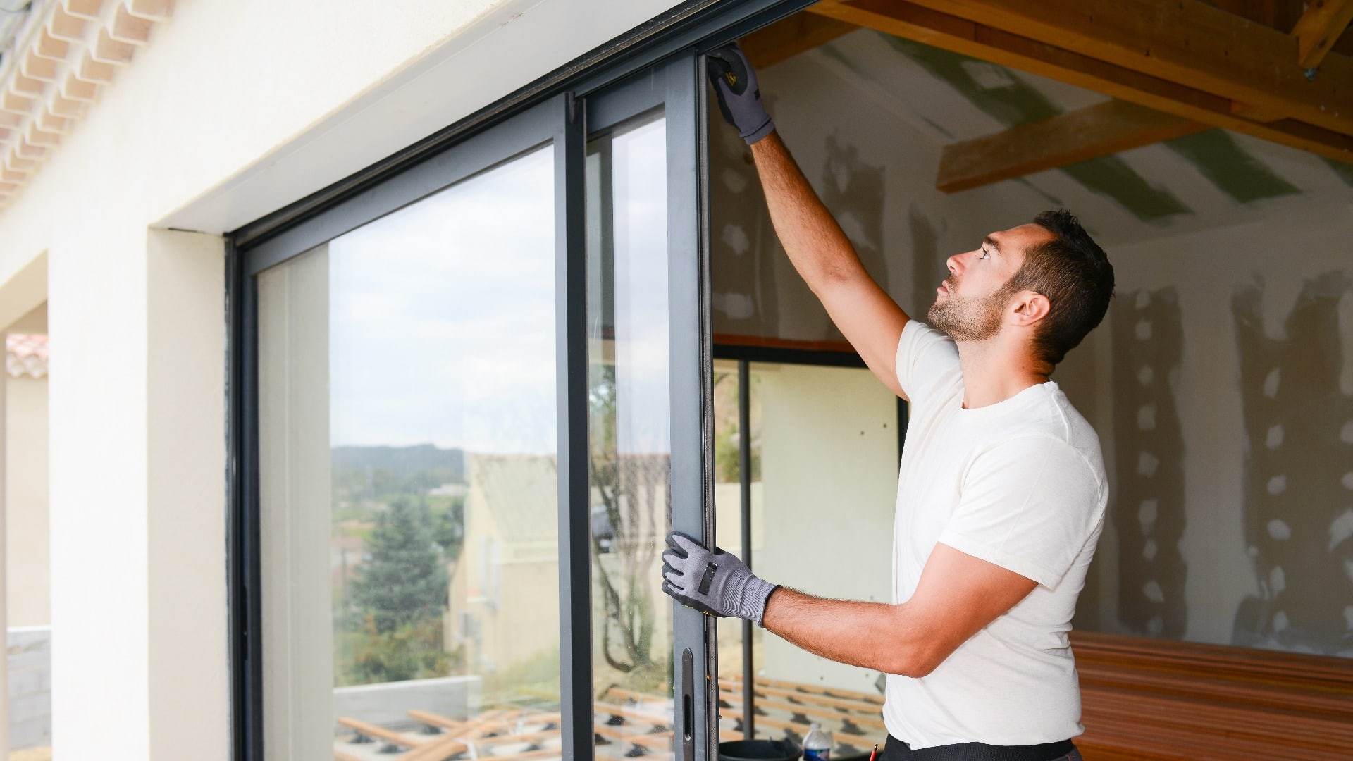 handsome young man installing bay window in a new house construction site