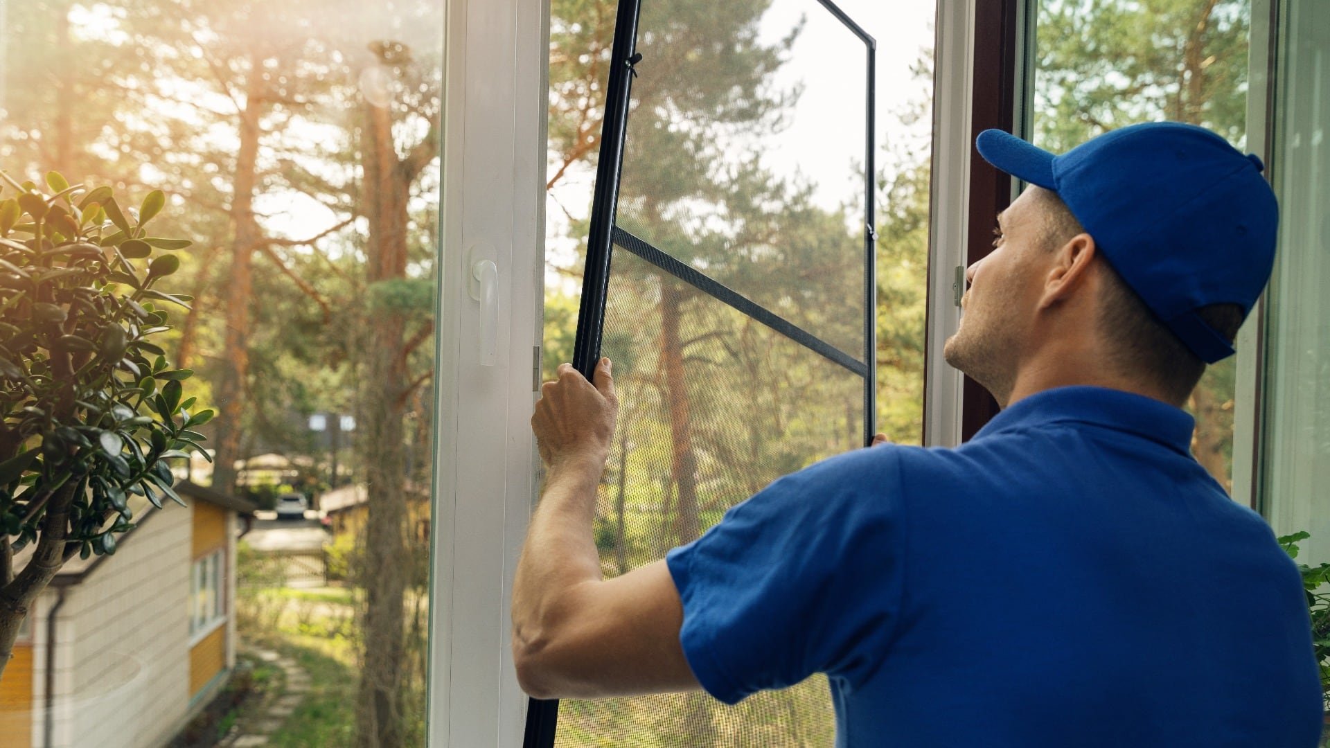 worker installing mosquito net wire screen on house window